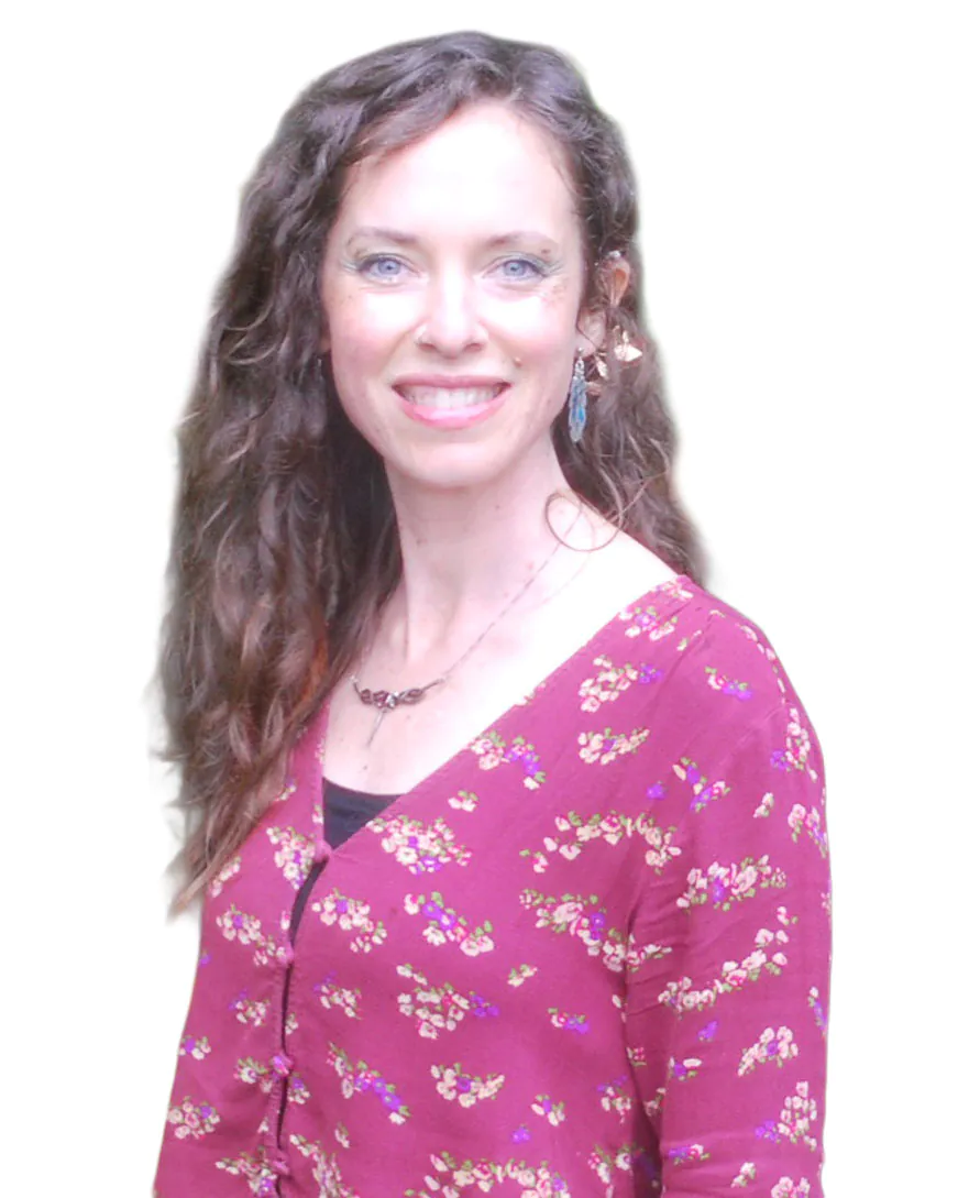A woman with curly hair smiles, wearing a floral-patterned maroon cardigan and jewelry against a plain background.